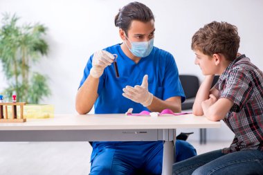 Genç çocuk hastanede doktoru ziyaret ediyor.
