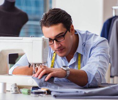 Genç terzi yeni elbiseler üzerinde çalışıyor.