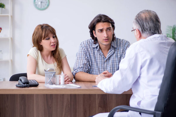 Молодая пара, посещающая пожилого врача