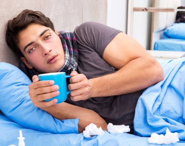 Grip olmuş hasta adam yatakta yatıyor.