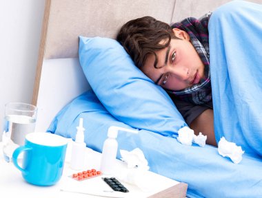 Grip olmuş hasta adam yatakta yatıyor.