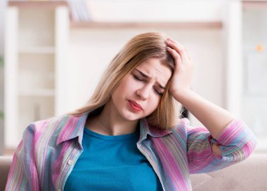 Evde acı çeken genç bir kadın.