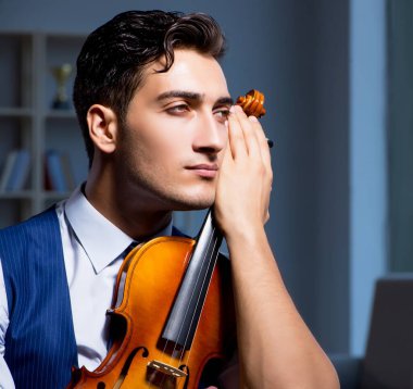 Genç müzisyen evde keman çalıyor.