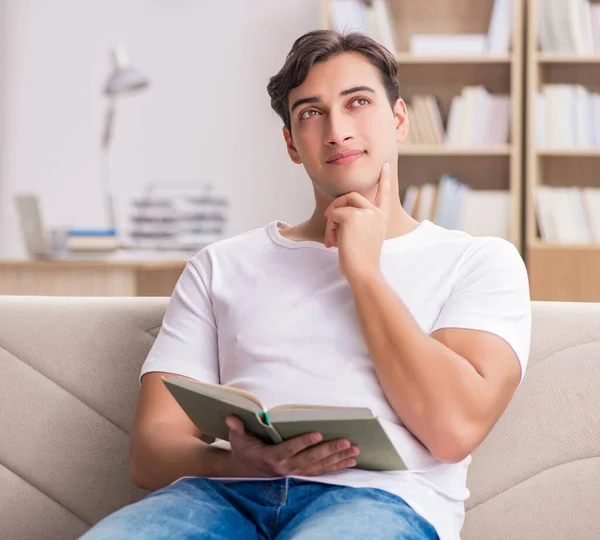 Чоловік читає книгу, сидячи в дивані — стокове фото