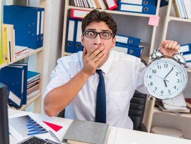 Ofiste kitap ve kağıtlarla çalışan bir işadamı.