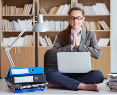 İş kadını ofiste meditasyon yapıyor.