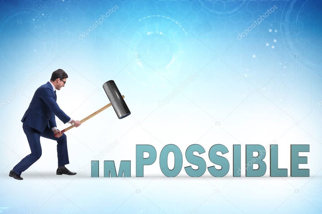 Businessman hitting the word impossible with hammer