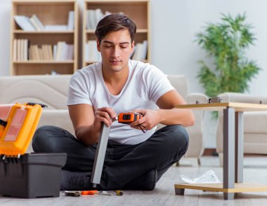 Adam evde mobilya montajı yapıyor.