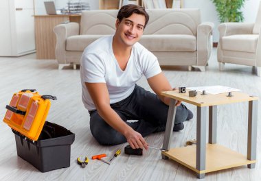 Adam evde mobilya montajı yapıyor.