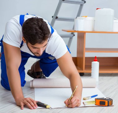 Tamirci, duvar kağıdıyla evde tadilat yapıyor.