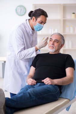 Yaşlı adam estetik ameliyat için genç doktoru ziyaret ediyor.