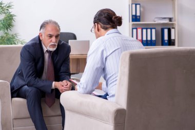 Yaşlı adam genç erkek doktor psikologunu ziyaret ediyor.