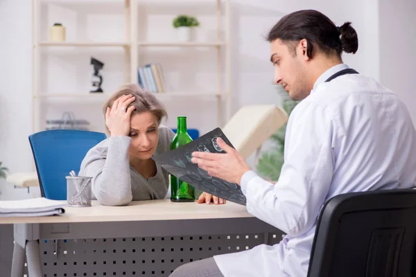 Mulher alcoólica visitando jovem médico masculino — Fotografia de Stock