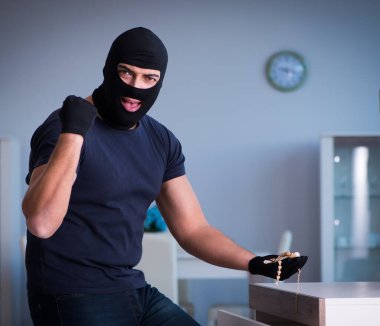 Soyguncu kar maskesi takıp değerli şeyler çalıyor.