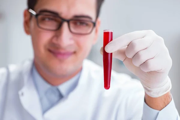 Médico joven en el laboratorio con tubo rojo — Foto de Stock