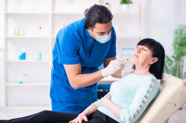 Yaşlı kadın estetik ameliyat için erkek doktoru ziyaret ediyor.