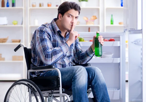 Young disabled injured man opening the fridge door