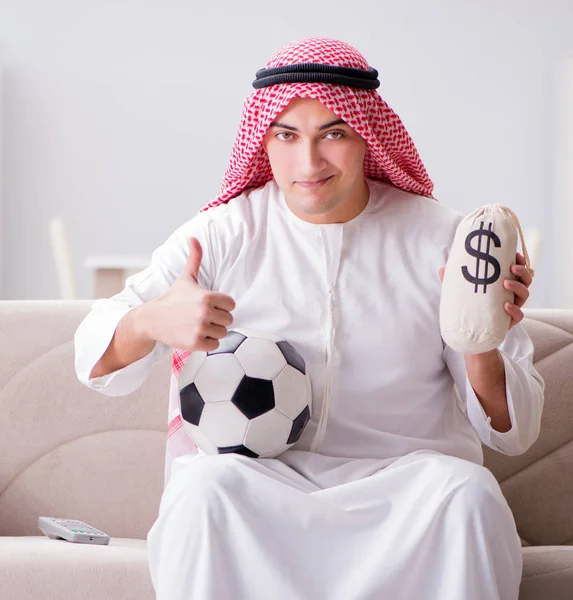 Genç Arap adam kanepede oturmuş futbol seyrediyor. — Stok fotoğraf