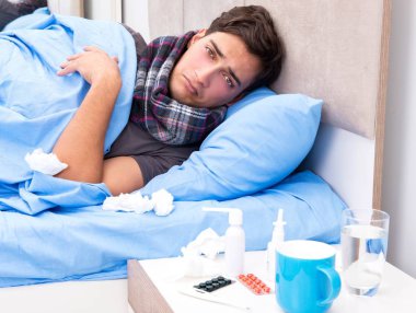 Grip olmuş hasta adam yatakta yatıyor.