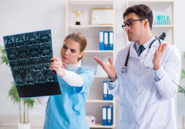 İki doktor teşhis için hastanın röntgen görüntülerini inceliyor.