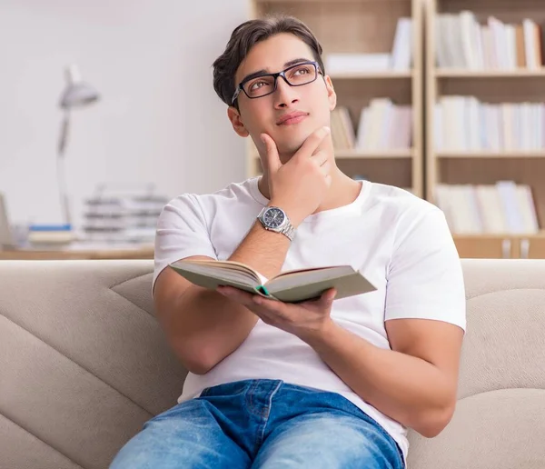 Hombre leyendo libro sentado en sofá sofá — Foto de Stock