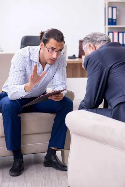 Oude man op bezoek bij jonge mannelijke dokter psycholoog — Stockfoto