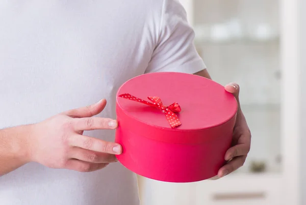 Young man with gift bag at home preparing suprise for wife — Stock Photo, Image