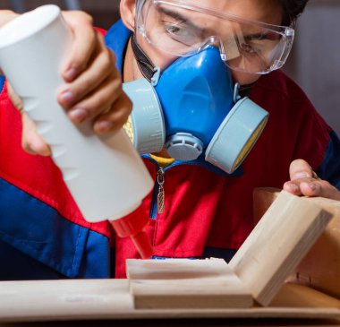 Genç adam ahşap parçaları DIY konseptinde yapıştırıyor.