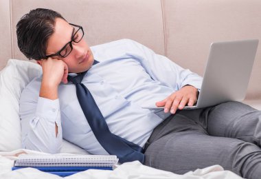 İş adamı evdeki yatakta çalışıyor.