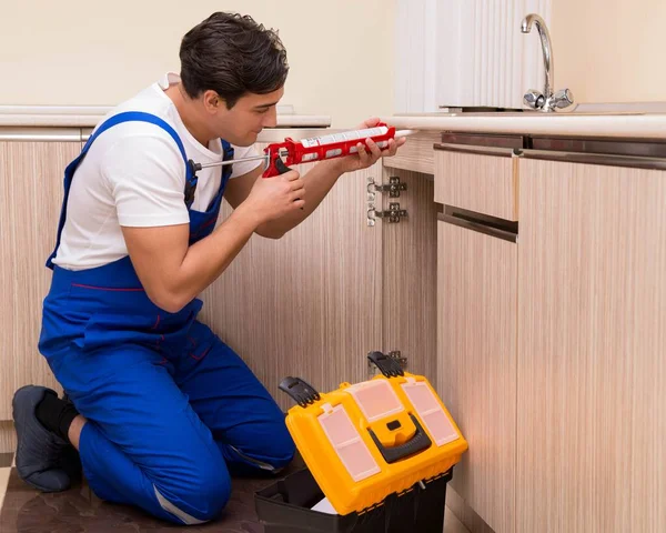 Jonge reparateur werkt in de keuken — Stockfoto