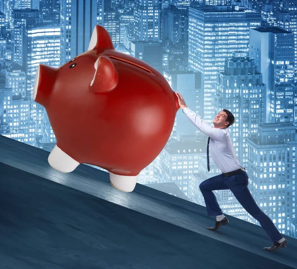 Hombre empujando a Piggybank cuesta arriba en concepto de negocio —  Fotos de Stock