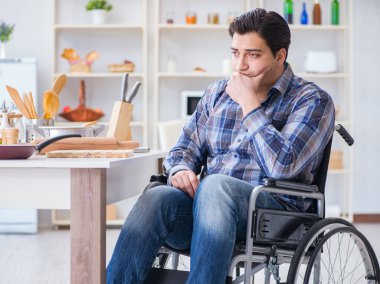 Engelli genç koca mutfakta çalışıyor.