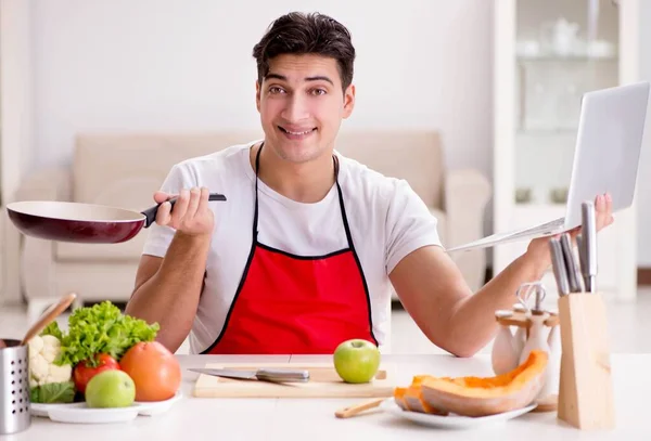 Homem com laptop preparando comida na cozinha — Fotografia de Stock