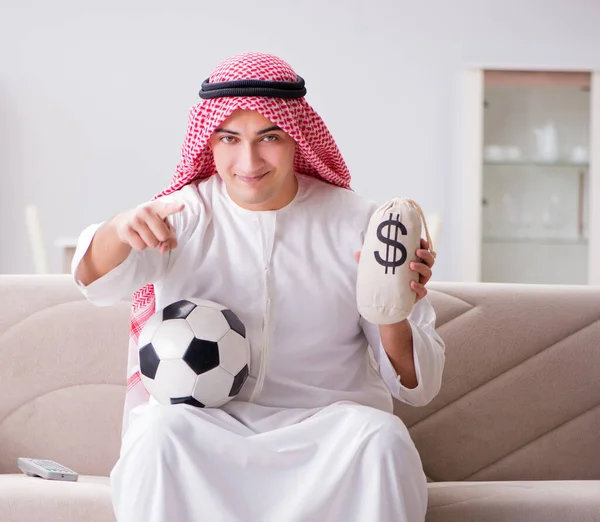 若いですarab男見サッカー座っています上のソファ — ストック写真