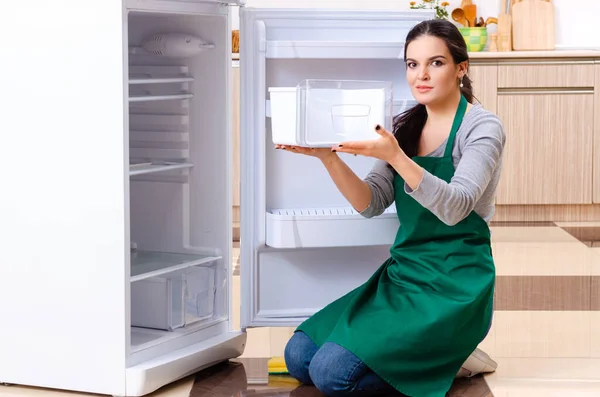 Mujer joven limpiando nevera en concepto de higiene — Foto de Stock