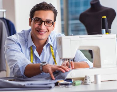 Genç terzi yeni elbiseler üzerinde çalışıyor.