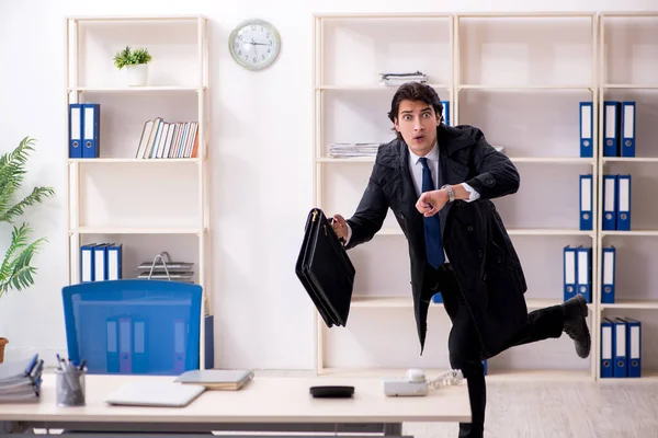 Jonge mannelijke werknemer in het kantoor in time management concept — Stockfoto