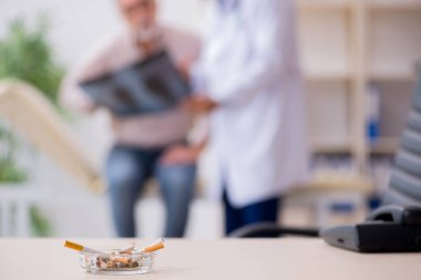 Sigara karşıtı genç erkek doktor ve yaşlı hasta