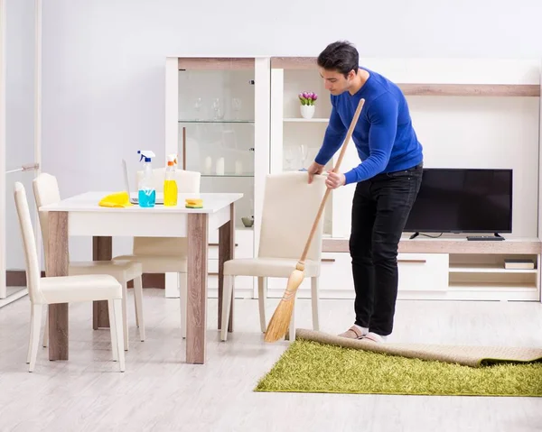 Młody człowiek sprzątanie podłogi miotłą — Zdjęcie stockowe
