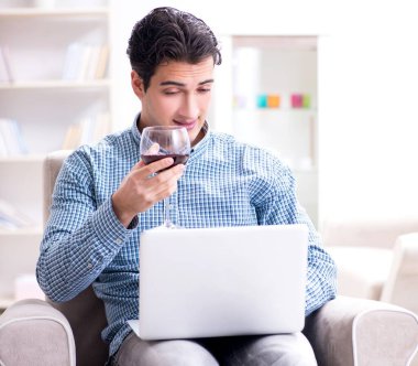 Genç adam evde şarap içiyor.
