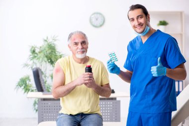 Yaralı yaşlı adam genç erkek doktor travmatoloğu ziyaret ediyor.