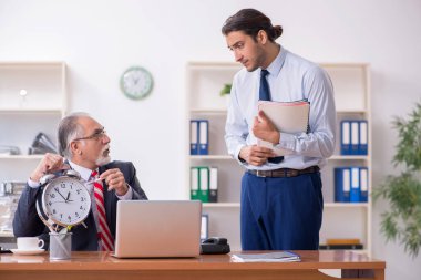 Eski patron ve genç erkek çalışan ofiste.