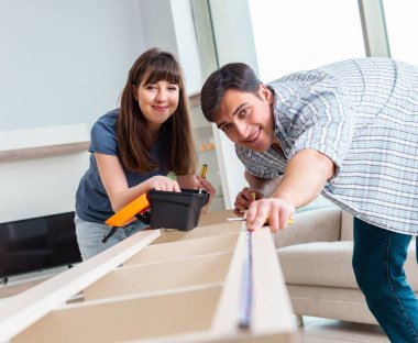 Yeni evde mobilya montajı yapan genç bir aile.