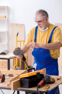 Yaşlı erkek marangoz atölyede çalışıyor.