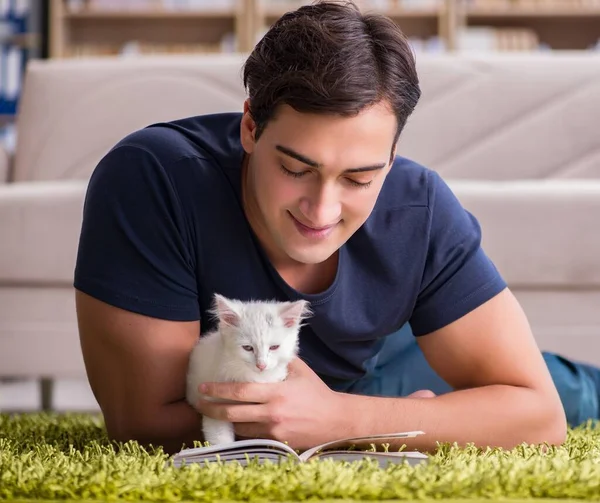 Молодой красивый мужчина играет с белым котенком — стоковое фото