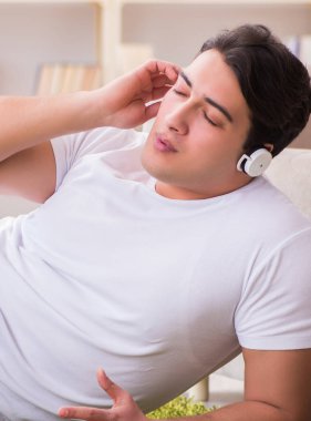 Evde müzik dinleyen genç bir öğrenci.