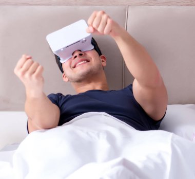 Yatakta sanal gerçeklik gözlüklü eş ve koca.