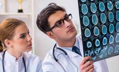 İki doktor teşhis için hastanın röntgen görüntülerini inceliyor.