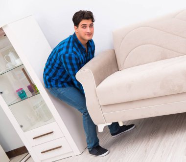 Genç adam kanepeyi taşıyor.