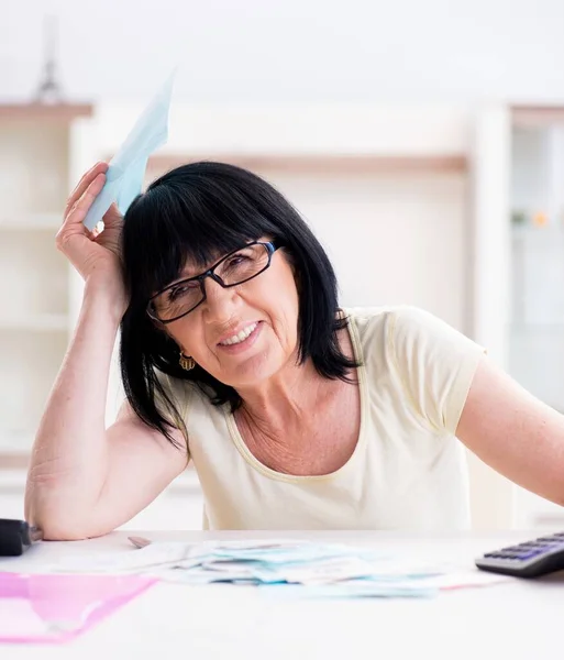 Reife Frau versucht, ihre Rechnungen unter einen Hut zu bringen — Stockfoto